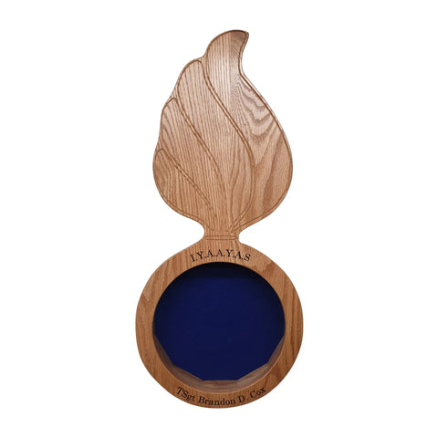 The Legacies of America Woodworking Company Oak Ammo Pisspot Shadow Box is a flame-shaped wooden plaque with I.Y.A.A.Y.A.S. above a blue empty glass circle and TSgt Brandon D. Cox engraved on the base.