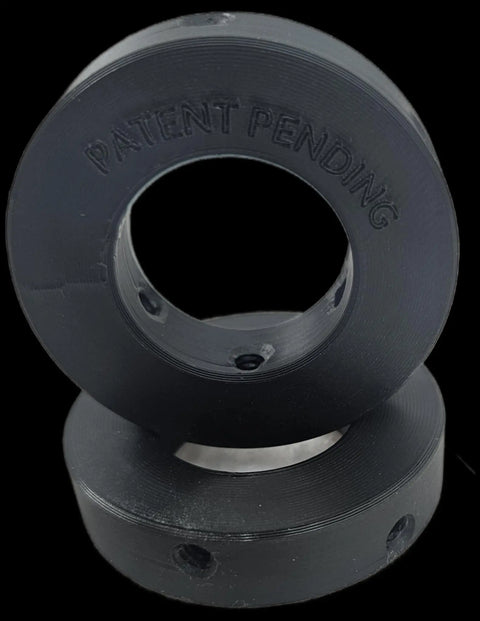 Two black circular plastic Olympic Plate to Standard Bar Adapters (2 to 1) by Weight It Out are stacked together. The top ring has PATENT PENDING engraved and small holes along the edge, ideal for home gym use.