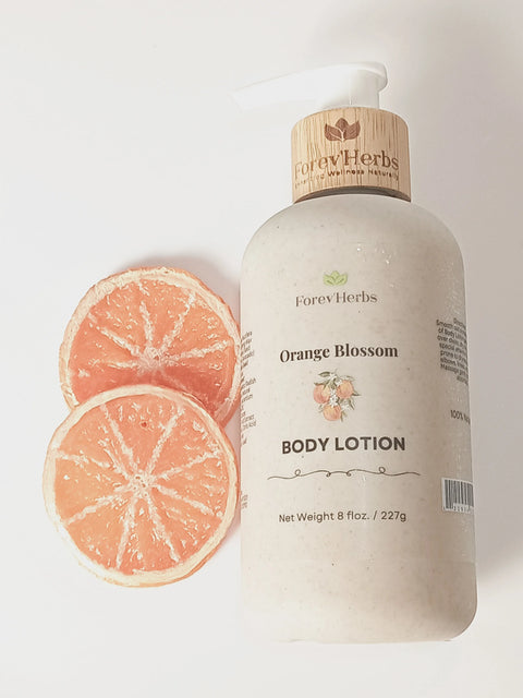 A bottle of Forev'Herbs Orange Blossom Lotion with a pump, infused with sweet orange essential oil, is placed beside two dried orange slices on a white surface—a natural moisturizer for glowing skin.