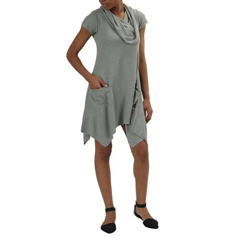 A person wears the Colette Drape Dress by Spiritex | Sustainable Apparel—a short-sleeved, light gray bamboo jersey dress with large front pockets and an asymmetrical hem—paired with black ankle-strap flats.