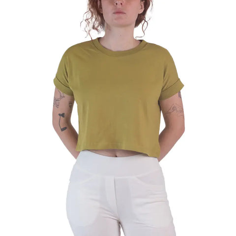 A person with curly hair wears a Spiritex Roan Crop Top in olive green, made from 100% organic cotton, and high-waisted white pants against a plain white background—embracing sustainable fashion.