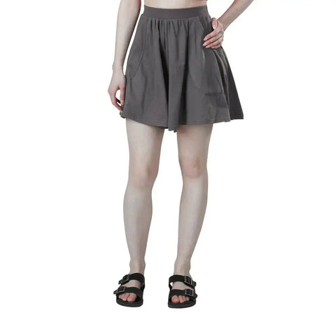 A person stands with one hand on their hip, wearing Spiritex | Sustainable Apparel Drape Shorts. The image, cropped at the shoulders against a white background, highlights this stylish gray piece—ideal for a summer wardrobe.