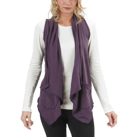 A woman wears the Spiritex Ultra Lightweight Draped Vest—an organic cotton layering piece—over a white long-sleeve shirt and black pants, standing forward with arms slightly out, her face partially out of frame.