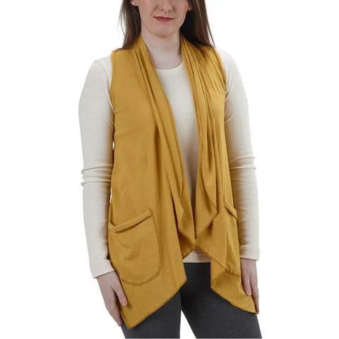 A woman wears the Ultra Lightweight Draped Vest by Spiritex | Sustainable Apparel in mustard yellow over a long-sleeve cream organic cotton shirt with front pockets, paired with dark leggings. Image cropped from shoulders to hips.