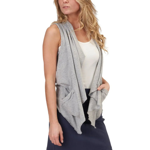 A woman wears the Ultra Lightweight Draped Vest by Spiritex | Sustainable Apparel over a white sleeveless top and navy skirt, with her left hand in the vest pocket, standing against a plain white background.
