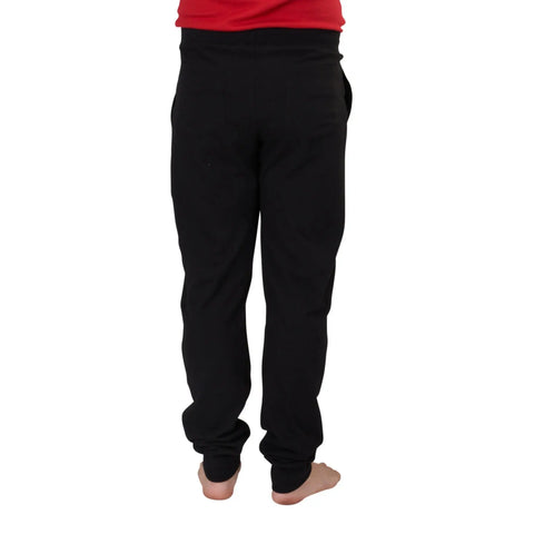 A person stands barefoot, facing away from the camera, wearing Spiritex | Sustainable Apparel Drawstring Jogger Pants in black with a relaxed fit, adjustable drawstring waistband, and a red shirt. Their feet are slightly apart.