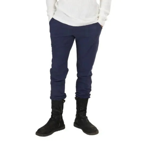 A person wearing white ribbed sweater, Spiritex | Sustainable Apparel Drawstring Jogger Pants, and black boots stands with hands in pockets against a white background.