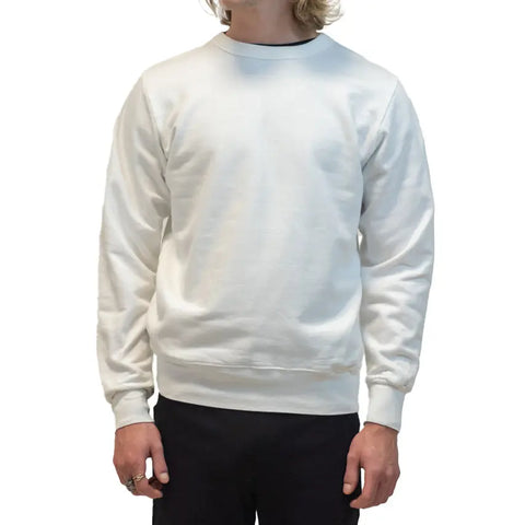 A person with shoulder-length blond hair wears the Spiritex | Sustainable Apparel Fleece Crewneck Sweatshirt in white and black pants. The head is partially out of frame against a solid white background.