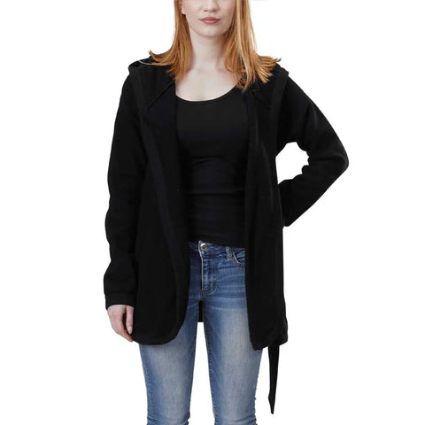 A woman with straight, shoulder-length red hair wears the Spiritex Fleece Wrap Jacket, a black open-front piece, over a black top and blue jeans, standing against a plain white background.