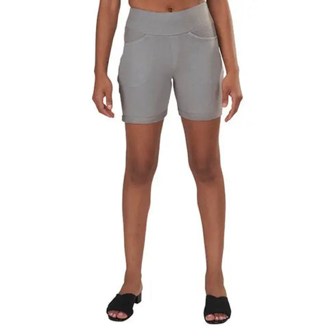 A person stands facing forward in Spiritex Saratoga Shorts, featuring front pockets and a light gray hue. Cropped below the waist, these comfortable womens shorts are paired with black open-toe sandals against a plain white background.