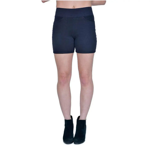A model showcases Spiritex | Sustainable Apparels Saratoga Shorts—high-waisted, dark womens shorts—paired with black ankle boots against a white background. The image crops out the upper torso and head.