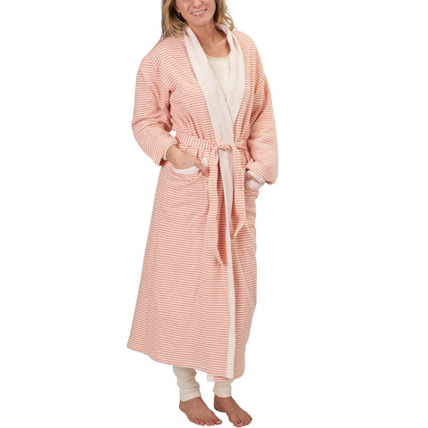 A woman smiles in the Spiritex | Sustainable Apparel Full-Length Fleece Robe, featuring pink and white stripes, a belt, front pockets, and lightweight fleece. She stands with her hands in the pockets over light pajamas.