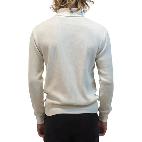 A person with medium-length blond hair is shown from the back, wearing the Spiritex | Sustainable Apparel Lexington Thermal Top in heavyweight waffle knit and dark pants, standing against a plain white background.