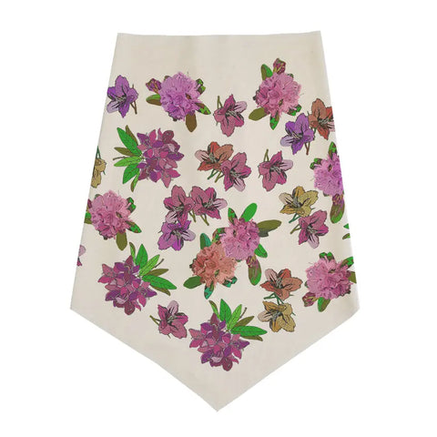 The Infinity Bandana by Spiritex | Sustainable Apparel is cream-colored with a pointed tip, showcasing pink, purple, and brown flowers with green leaves on organic cotton fabric.