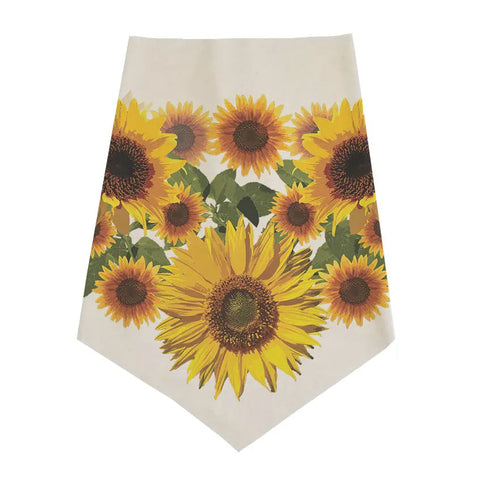 A cream-colored table runner with bold yellow sunflowers and green leaves, crafted with the same care and quality as Spiritex | Sustainable Apparel’s Infinity Bandana.