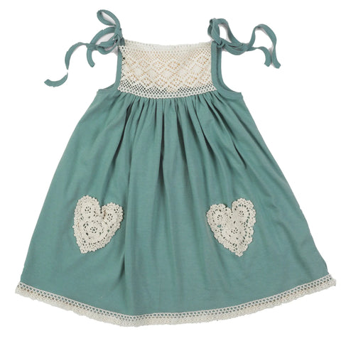 The Spiritex | Sustainable Apparel Lace Pocket Dress is a sleeveless teal A-line design for children, featuring lace detail on the chest, lace heart pockets on the skirt, tied shoulder straps, and a gathered waist.