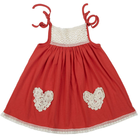 The Lace Pocket Dress by Spiritex | Sustainable Apparel is a sleeveless red A-line childrens dress featuring white lace trim, heart-shaped lace pockets on the front, thin shoulder straps tied in bows, and a white lace chest panel.