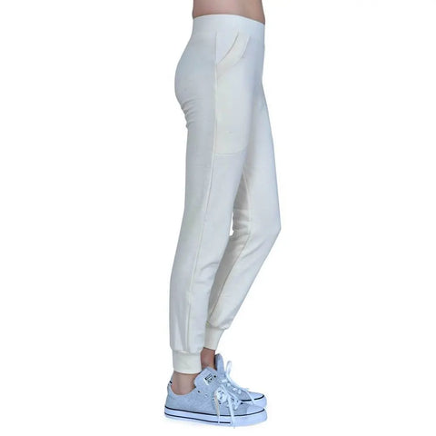 A person wears Lightweight Jogger Pants in cream by Spiritex | Sustainable Apparel, featuring side pockets, paired with gray low-top sneakers. The side view is set against a plain white background.