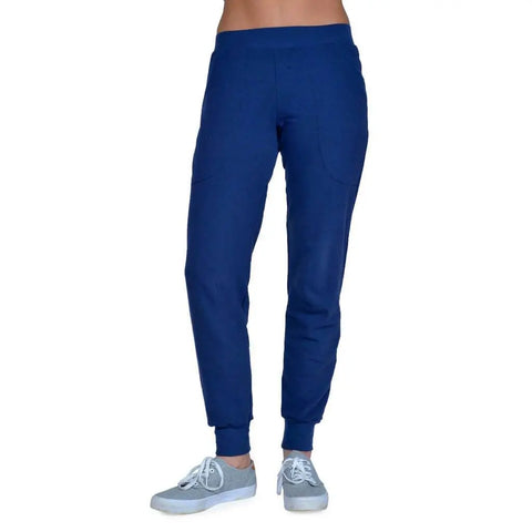 A person is shown from midriff down wearing Spiritex | Sustainable Apparel Lightweight Jogger Pants in blue and light gray sneakers, standing against a white background.