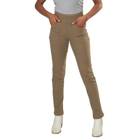 A person models the Lightweight Saratoga Pants by Spiritex | Sustainable Apparel—tan, high-waisted, organic cotton—paired with a tucked-in light gray top and white ankle boots, standing hands-in-pockets against a white background.