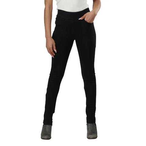 A person models Spiritex | Sustainable Apparel’s Lightweight Saratoga Pants in black, paired with a white top and gray ankle boots, standing with one hand in a pocket against a white background.