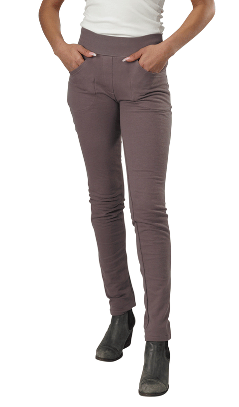 A person models Spiritex | Sustainable Apparels Lightweight Saratoga Pants in mauve organic cotton, paired with a white top and black ankle boots, standing with hands in pockets against a white background.