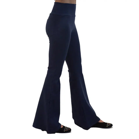A person wearing Spiritex | Sustainable Apparel Lycra Bell Bottoms in high-waisted dark navy blue organic cotton with black studded flats, shown from the side against a plain white background.