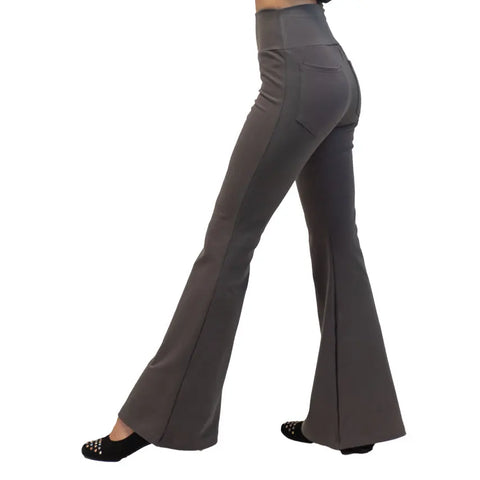 A person is shown from the waist down, walking in Spiritex | Sustainable Apparel Lycra Bell Bottoms—high-waisted and grey—made with organic cotton, paired with black studded shoes, viewed from the side.