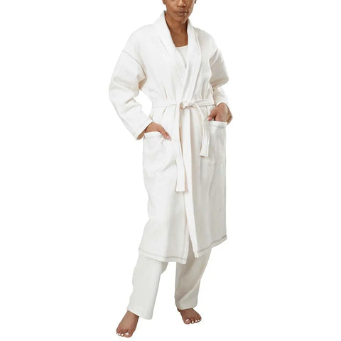 A person stands barefoot on a white background wearing the Spiritex | Sustainable Apparel Mid-Length Fleece Robe, a white unisex style with large front pockets and a waist tie.
