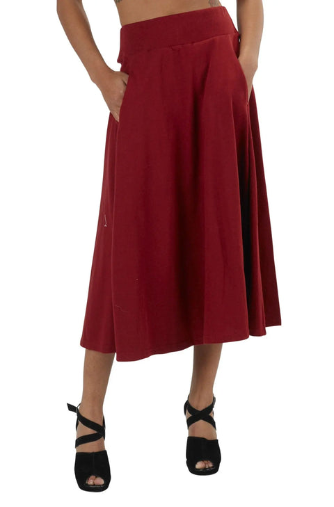 A person wears a high-waisted, knee-length red Gore Skirt with pockets by Spiritex | Sustainable Apparel, paired with black open-toe heels. The upper body is cropped out of the image.