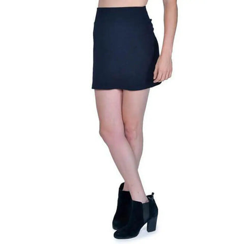 A person models the black Andy Skirt by Spiritex | Sustainable Apparel with black ankle boots, standing against a plain white background to highlight this eco-friendly fashion choice.