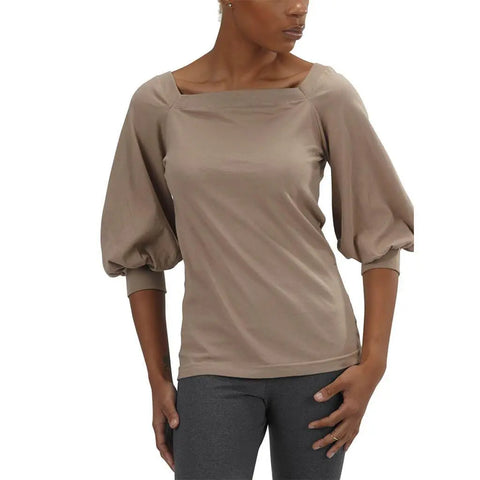 A woman wears the Spiritex | Sustainable Apparel Romantic Top in taupe organic cotton with a square neckline and wide three-quarter bishop sleeves, paired with dark gray leggings, standing against a white background.