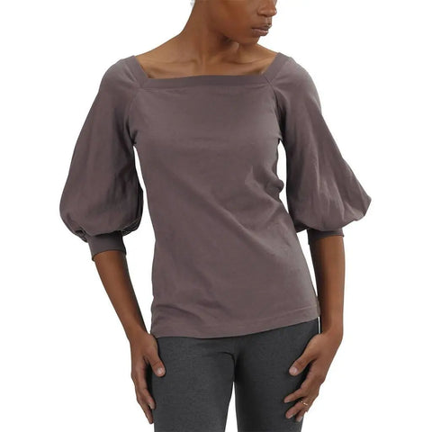 A person models the Spiritex Romantic Top—an organic cotton mauve, three-quarter sleeve top with a square neckline—paired with gray leggings, standing hands on hips against a plain white background.