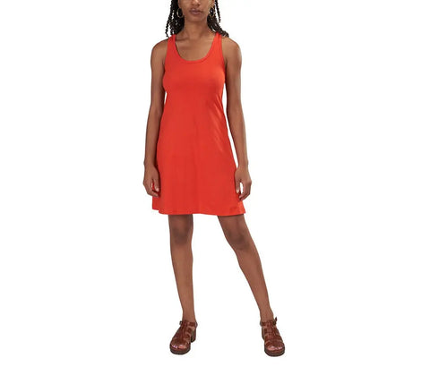 A woman stands against a white background, wearing the Spiritex | Sustainable Apparel Racerback Tank Dress in red-orange with brown sandals—an ideal capsule wardrobe piece. Her arms are relaxed by her sides and one leg is slightly bent.