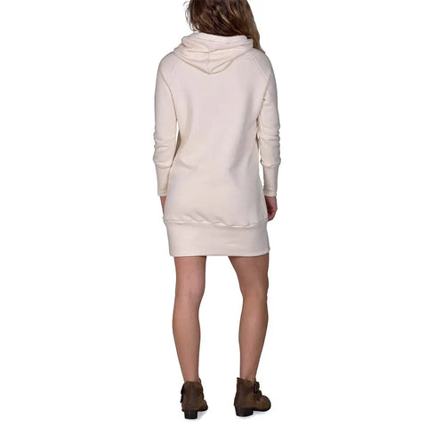 A person facing away wears a cream RAD Sweatshirt Dress by Spiritex | Sustainable Apparel with brown ankle boots. The dresss hood is up but not on the head, and the background is plain white.