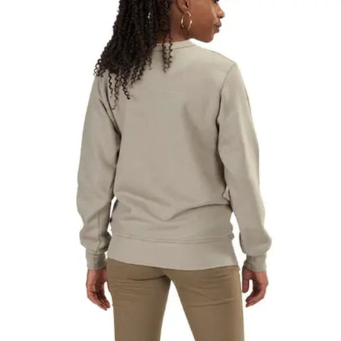 A woman with curly hair, wearing the Spiritex | Sustainable Apparel V-Inset Crewneck Sweatshirt in light beige and khaki pants, stands facing away from the camera.