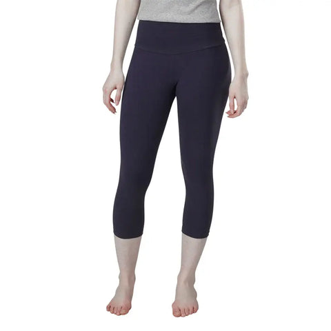 A person stands barefoot in a gray top and dark blue high-waisted Spiritex | Sustainable Apparel Yoga Capri leggings made from organic cotton against a plain white background. Their face is not visible.