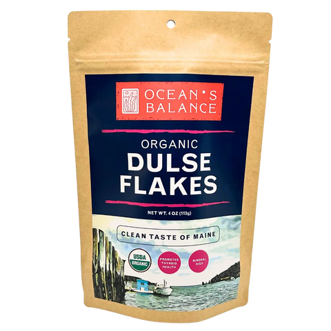 A brown resealable bag labeled Oceans Balance Organic Dulse Flakes features coastal art, USDA Organic seal, and promotes heart health with mineral-rich seaweed flakes. Net weight: 4 oz (113 g).