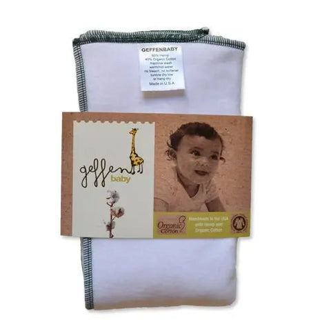 A white Geffenbaby Cloth Prefold Diaper with green edging is shown, labeled super absorbent fleece hemp and organic cotton. Packaging features a smiling baby, cartoon giraffe, cotton plant, and notes its handmade in the USA.