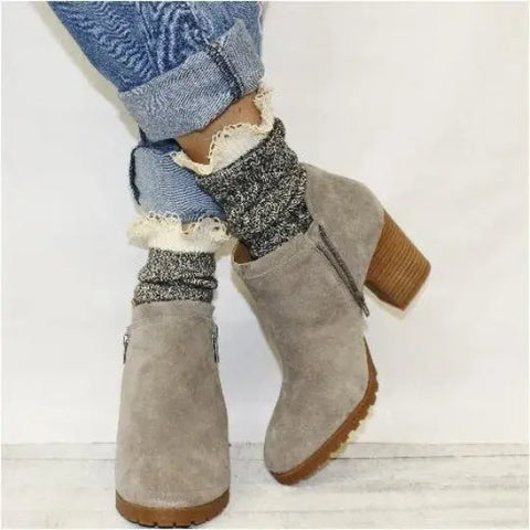 Someone stands with feet crossed, wearing rolled-up jeans, taupe suede heeled ankle boots, and Catherine Cole ORGANIC Lace Boot Crew Socks in Salt N Pepper.