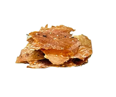 A small stack of thin, crispy, reddish-brown Nori Sesame Chicken jerky chips from Dogtown Bakery with visible seasoning and a hint of Hawaiian-inspired flavor, isolated on a white background.