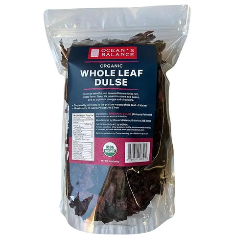 A clear plastic bag of Oceans Balance Organic Whole Leaf Dulse shows dark red dried seaweed inside. The blue label displays nutrition facts and certifications, including USDA Organic.