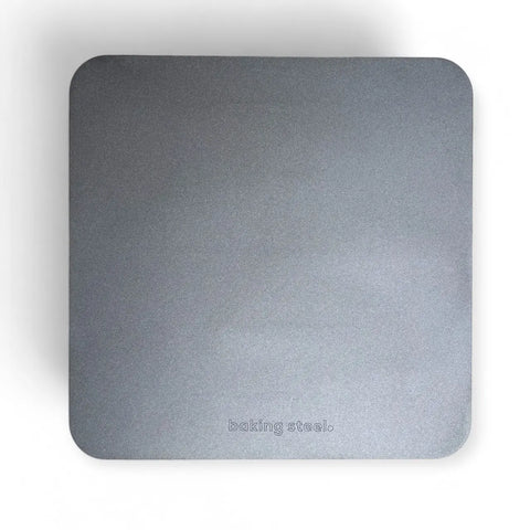A square, flat, gray Baking Steel Original by Baking Steel® with rounded corners sits on a white background. baking steel. is engraved near the bottom edge, making it ideal for baking pizza at home.