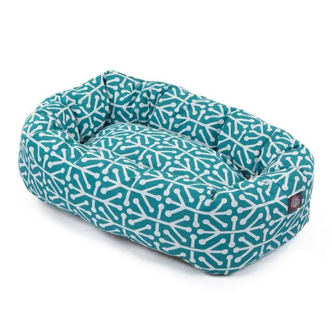 The Majestic Pet Aruba Bagel Dog Bed is a rectangular teal bed with raised sides, a white geometric interconnected lines pattern, and a small brand tag on one corner. This dog bed is also machine washable.
