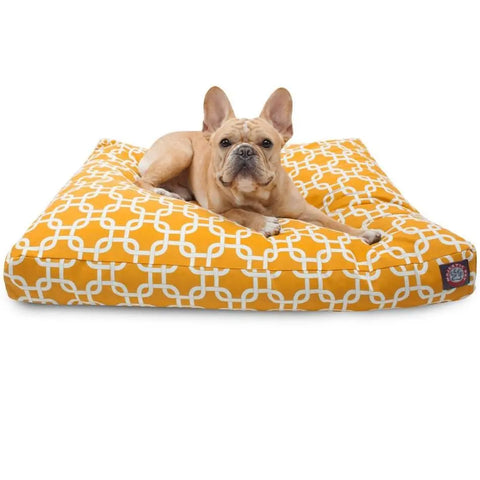 A fawn-colored French Bulldog rests on the Majestic Pet Links Memory Foam Dog Bed, featuring a large orange rectangle shape, white geometric pattern, and washable removable cover, looking at the camera against a white background.