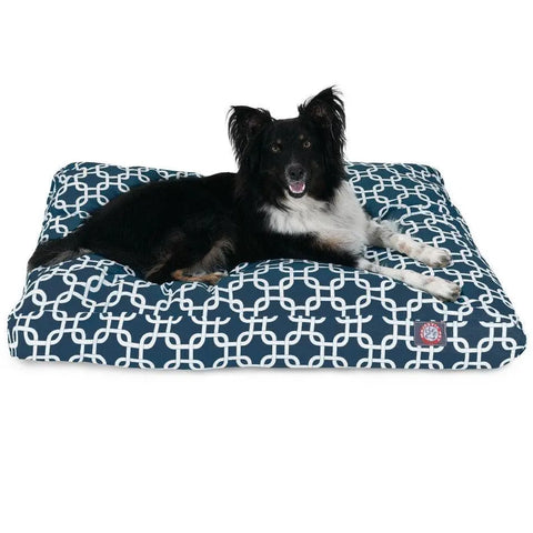 A black and white dog is lying on the Majestic Pet Links Memory Foam Dog Bed, which is navy blue with a white geometric pattern and features a removable, washable cover.