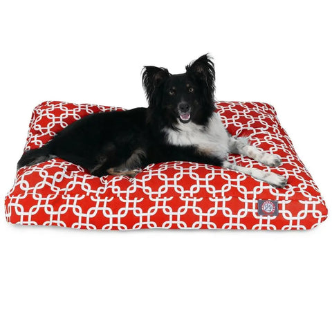 A black and white dog rests on the Majestic Pet Links Memory Foam Dog Bed with a red and white geometric cover. Filled with shredded memory foam, the washable, removable cover keeps it easy to clean for lasting comfort.