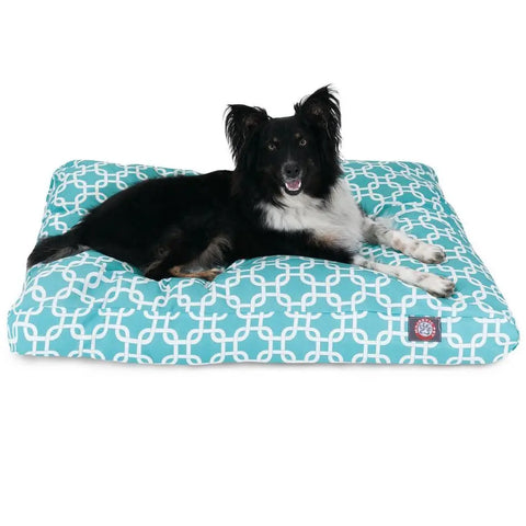 A black and white dog relaxes on the Majestic Pet Links Memory Foam Dog Bed, featuring a large, rectangular shape with a blue and white pattern and a removable cover, looking forward with its mouth slightly open.