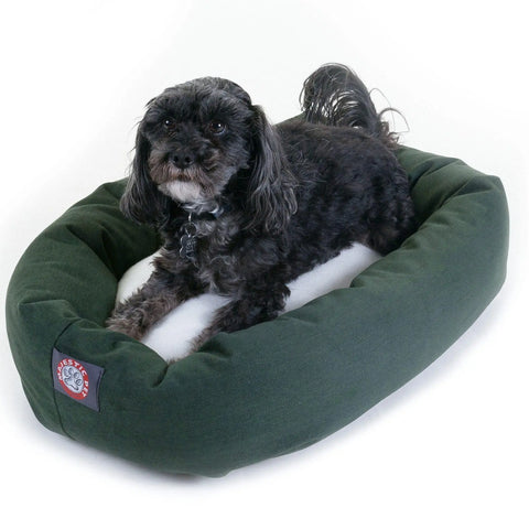 A small black dog with curly fur lies comfortably in a green and white Majestic Pet Poly/Cotton Sherpa Bagel Dog Bed, featuring a soft cushioned border, water-resistant fabric, and a tag on the front corner.