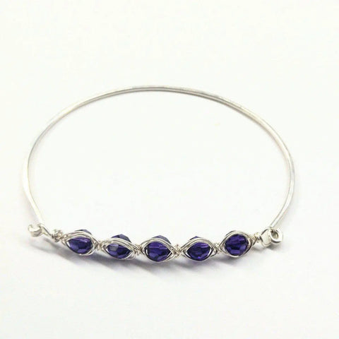 The Alexa Martha Designs Larger Oval Shaped Swarovski Crystal Bar Bangle Bracelet, designed for 8-inch wrists, features five deep purple crystals wrapped in silver wire, showcased on a white background.
